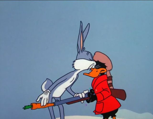 Bugs Bunny stuffs a carrot in Daffy's shotgun